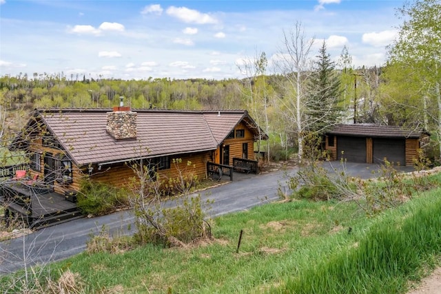 27845 County Road 41a, Steamboat Springs, CO 80487 - view of front of home with a forest view, a detached garage, a chimney, and an outbuilding