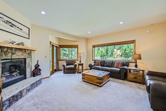 living area with carpet flooring, baseboards, a stone fireplace, and recessed lighting