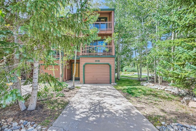 view of front of property featuring concrete driveway, a garage, and a balcony