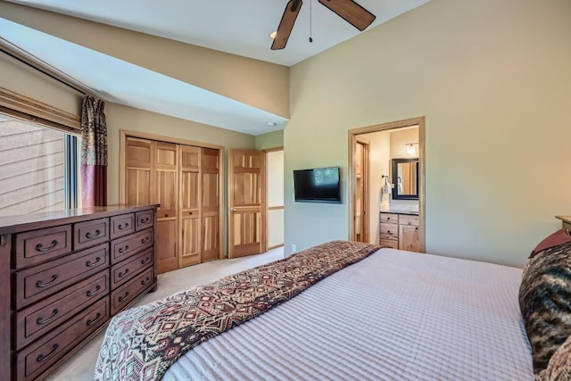 bedroom with a ceiling fan, a closet, connected bathroom, and light colored carpet
