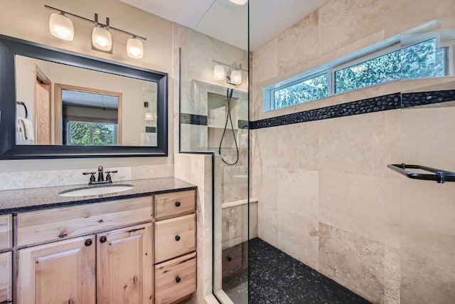 bathroom featuring vanity, a tile shower, and a healthy amount of sunlight