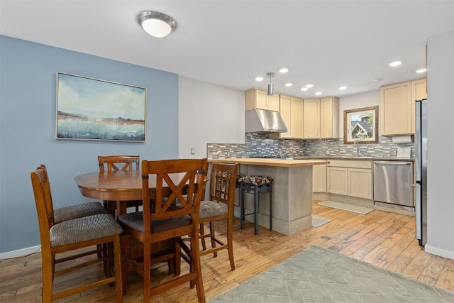 329 N Chipmunk Cir, Silverthorne, CO 80498 - kitchen featuring stainless steel appliances, exhaust hood, backsplash, light wood-style floors, and a peninsula
