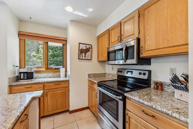 175 Argentine Ct Unit 1513, Keystone, CO 80435 - kitchen featuring appliances with stainless steel finishes, light tile patterned flooring, light stone counters, and brown cabinetry