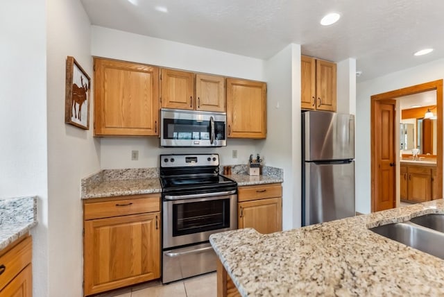 175 Argentine Ct Unit 1513, Keystone, CO 80435 - kitchen featuring appliances with stainless steel finishes, a sink, light stone counters, recessed lighting, and light tile patterned flooring