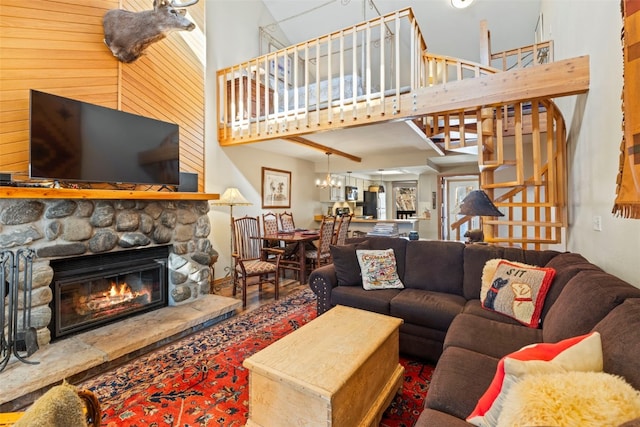 living area featuring a towering ceiling, a fireplace, a notable chandelier, and stairway