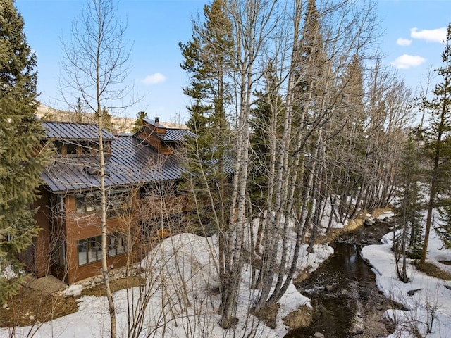 view of property exterior with a chimney, a standing seam roof, and metal roof