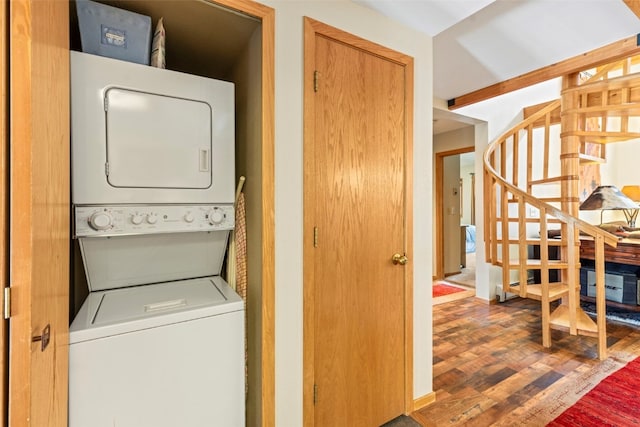 clothes washing area with wood finished floors and stacked washer and clothes dryer