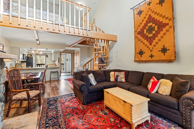 living room featuring wood finished floors, a high ceiling, a notable chandelier, and stairway