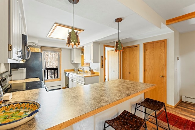 kitchen with a sink, a baseboard heating unit, a peninsula, appliances with stainless steel finishes, and a breakfast bar area