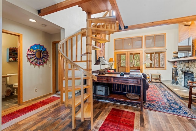 staircase with lofted ceiling with beams, baseboards, recessed lighting, hardwood / wood-style flooring, and a stone fireplace