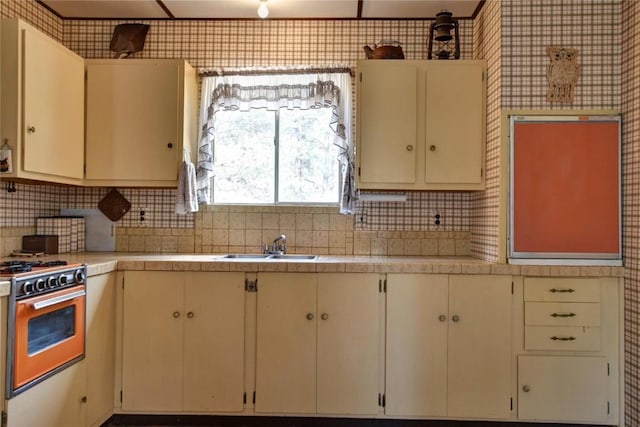 490 Teller St, Lake George, CO 80827 - kitchen featuring gas range, light countertops, backsplash, wallpapered walls, and cream cabinets