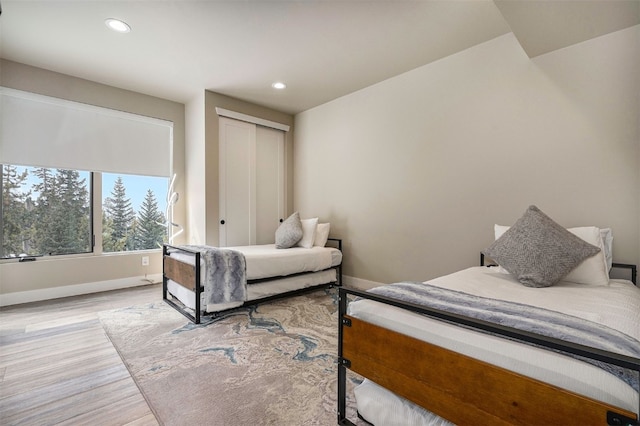 bedroom with light wood-type flooring, recessed lighting, baseboards, and a closet