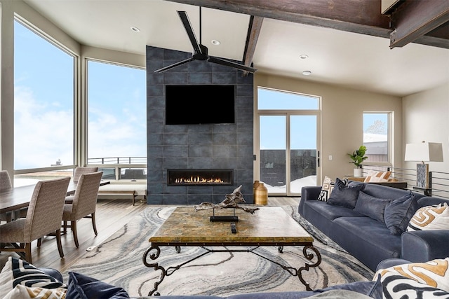 living room featuring ceiling fan, a tiled fireplace, wood finished floors, beamed ceiling, and recessed lighting