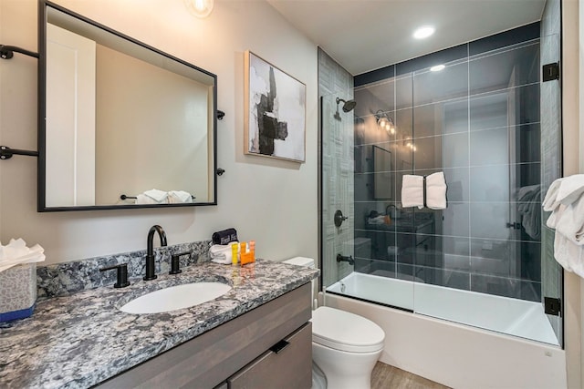 full bath with toilet, enclosed tub / shower combo, wood finished floors, and vanity
