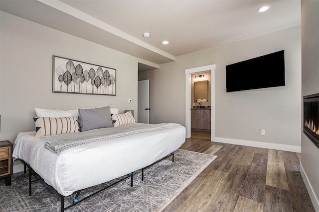 bedroom with baseboards, recessed lighting, connected bathroom, and wood finished floors
