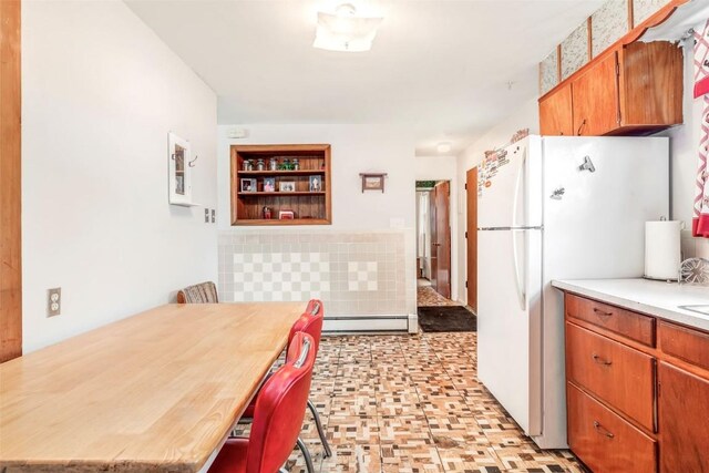149 N 2nd St, Hayden, CO 81639 - kitchen with light countertops, freestanding refrigerator, baseboard heating, and brown cabinets