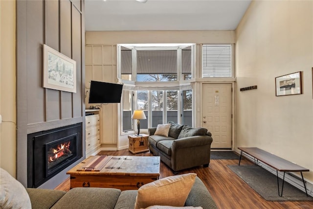 living area with a glass covered fireplace and wood finished floors