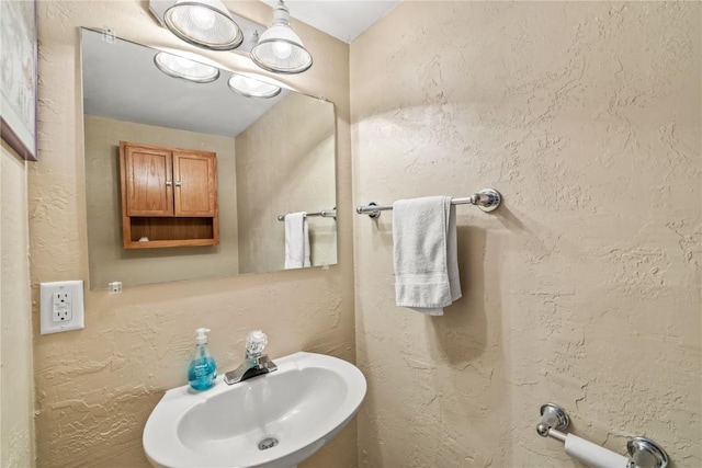 bathroom featuring a textured wall and a sink
