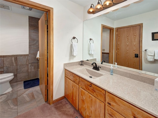 bathroom with tile walls, visible vents, toilet, and vanity