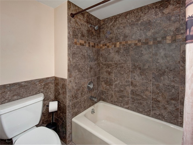 bathroom with tile walls, shower / bathtub combination, and toilet
