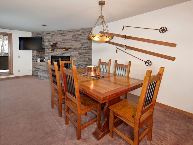 carpeted dining space with baseboards and a stone fireplace