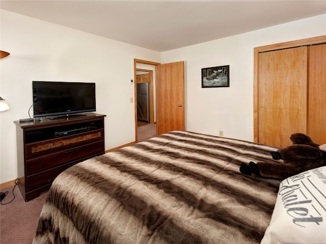 carpeted bedroom featuring freestanding refrigerator and a closet