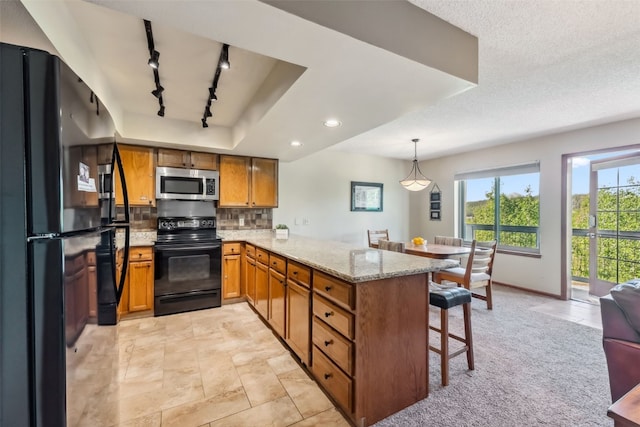 4612 Ryan Gulch Rd Unit 4612, Silverthorne, CO 80498 - kitchen with black appliances, a peninsula, brown cabinets, rail lighting, and a kitchen bar