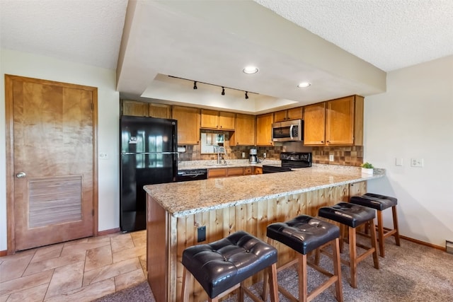 4612 Ryan Gulch Rd Unit 4612, Silverthorne, CO 80498 - kitchen featuring black appliances, a peninsula, backsplash, light stone counters, and a textured ceiling