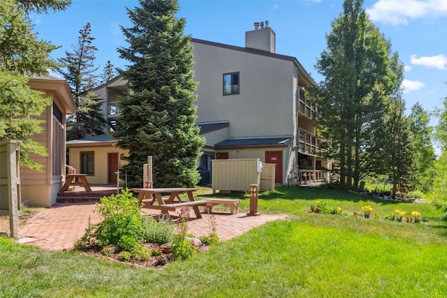 4612 Ryan Gulch Rd Unit 4612, Silverthorne, CO 80498 - rear view of property with a patio, a chimney, and a lawn