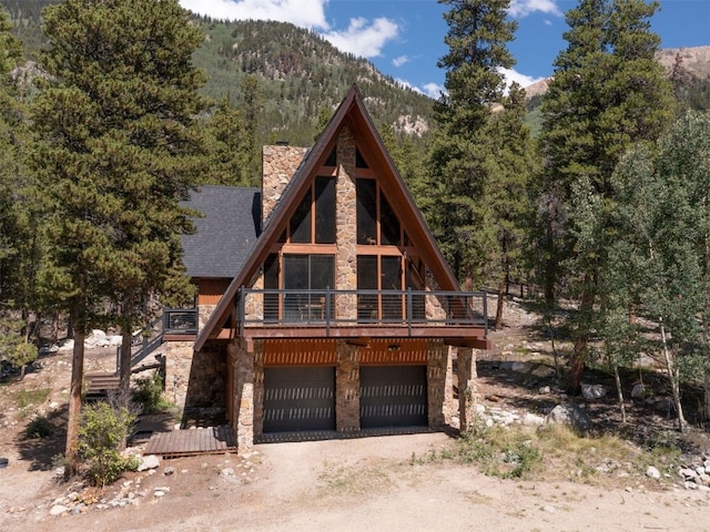 12715 E State Highway 82, Twin Lakes, CO 81251 - a-frame style home featuring stone siding, dirt driveway, an attached garage, and roof with shingles
