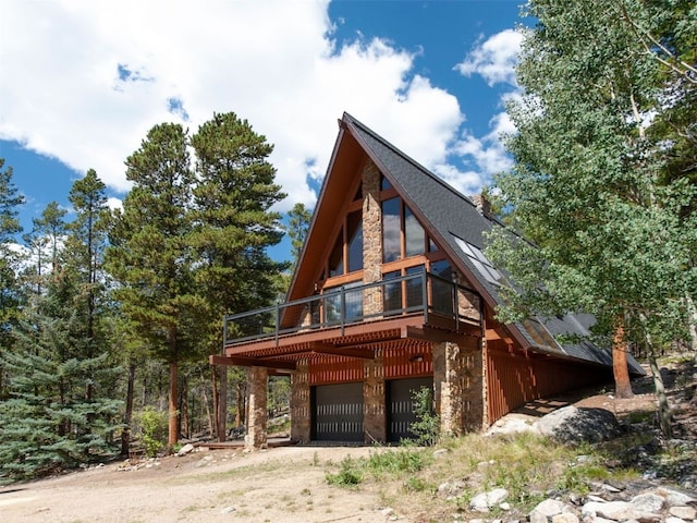 12715 E State Highway 82, Twin Lakes, CO 81251 - view of property exterior featuring dirt driveway, stone siding, a wooden deck, and an attached garage
