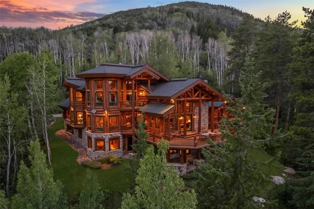 27800 Wapiti Way, Steamboat Springs, CO 80487 - back of property at dusk featuring a forest view, stone siding, a deck with mountain view, and log exterior