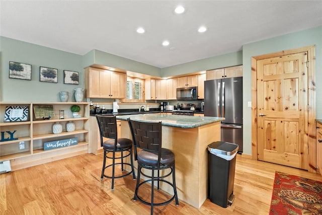 100 River Park Dr Unit 100A, Breckenridge, CO 80424 - kitchen with stainless steel appliances, light brown cabinetry, a breakfast bar area, a kitchen island, and light wood-style floors