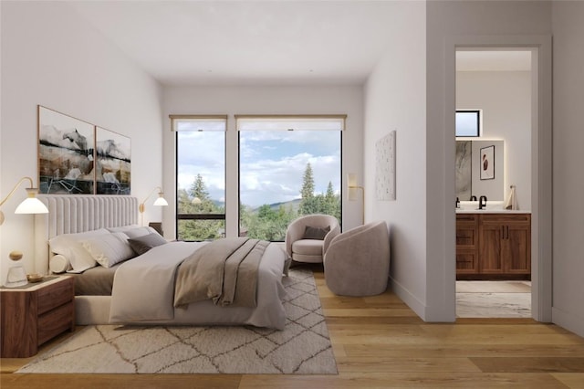bedroom with light wood-style floors, baseboards, a sink, and connected bathroom