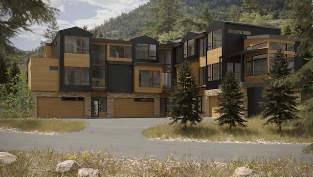 view of building exterior with an attached garage, a mountain view, and concrete driveway