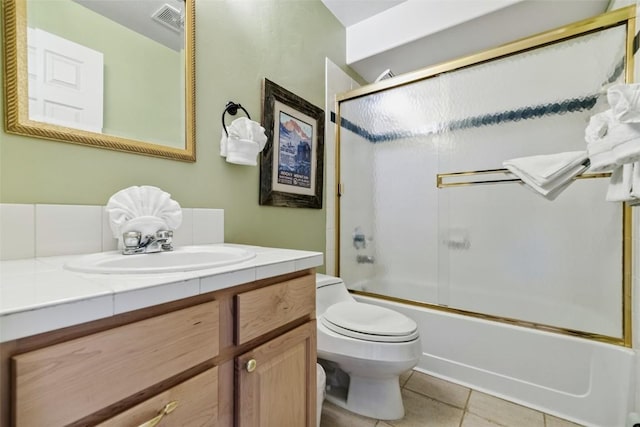 bathroom featuring tile patterned floors, visible vents, toilet, vanity, and bath / shower combo with glass door