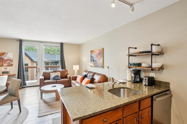129 River Run Rd Unit 8055, Keystone, CO 80435 - kitchen featuring a sink, dishwasher, brown cabinetry, light wood-type flooring, and light stone counters