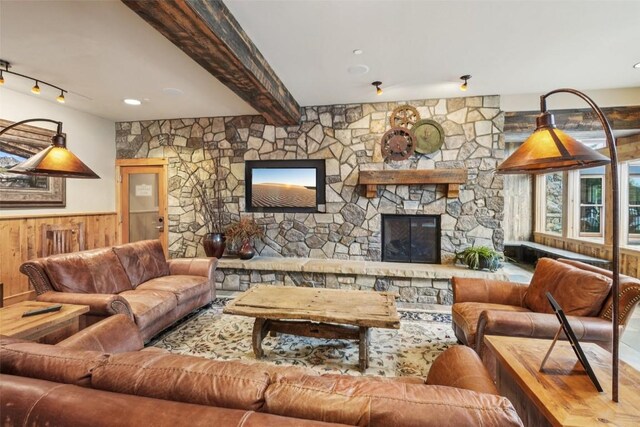 129 River Run Rd Unit 8055, Keystone, CO 80435 - living room with rail lighting, wainscoting, wooden walls, beam ceiling, and a stone fireplace