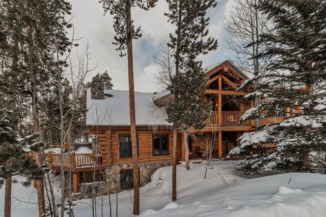 107 Primrose Pl, Frisco, CO 80443 - snow covered rear of property with stone siding, a chimney, log siding, and a balcony