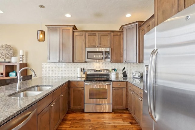 0050 County Road 1293 Unit B, Silverthorne, CO 80498 - kitchen featuring light stone counters, wood finished floors, a sink, brown cabinets, and appliances with stainless steel finishes