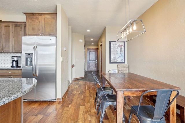0050 County Road 1293 Unit B, Silverthorne, CO 80498 - kitchen featuring hanging light fixtures, wood finished floors, brown cabinets, stainless steel fridge with ice dispenser, and light stone countertops