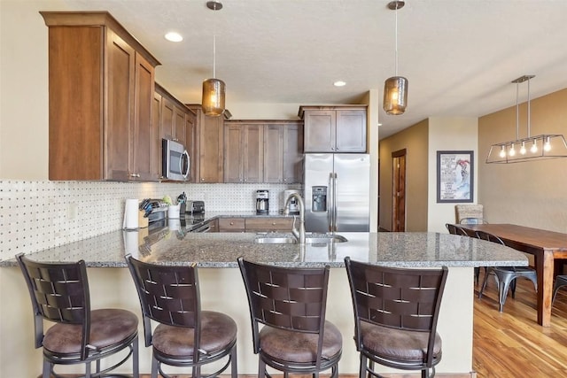 0050 County Road 1293 Unit B, Silverthorne, CO 80498 - kitchen featuring stainless steel appliances, backsplash, stone counters, a peninsula, and light wood-style flooring