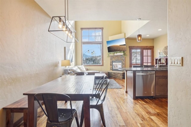 0050 County Road 1293 Unit B, Silverthorne, CO 80498 - dining room featuring a textured wall, a stone fireplace, light wood-style floors, and a healthy amount of sunlight