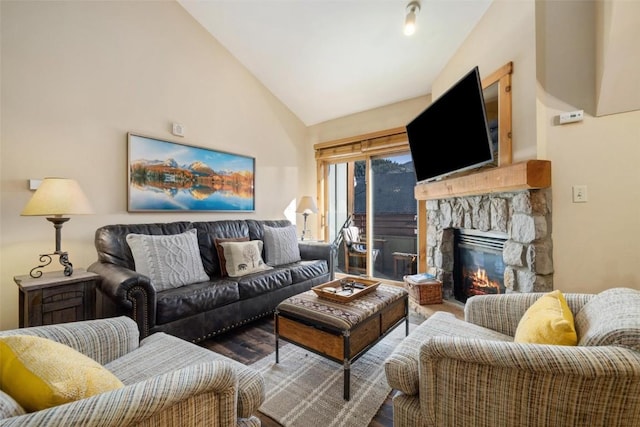 living room featuring a stone fireplace, lofted ceiling, and wood finished floors