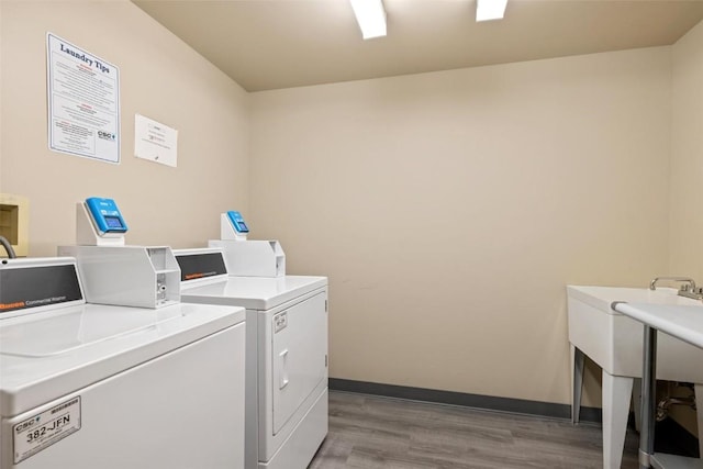 community laundry room featuring light wood finished floors, washing machine and clothes dryer, and baseboards