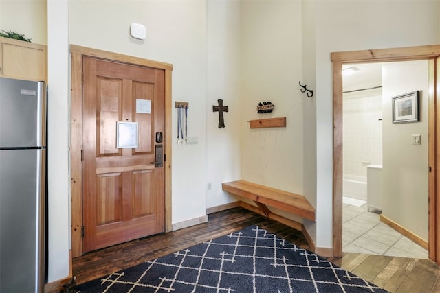 foyer featuring wood finished floors, a towering ceiling, and baseboards