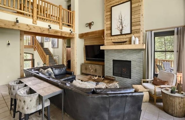 tiled living room with a tiled fireplace, a towering ceiling, and stairway