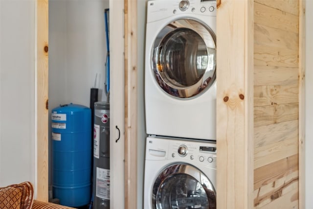 washroom with electric water heater, laundry area, and stacked washing maching and dryer
