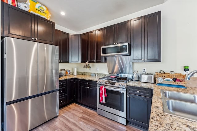 32 Wayback Dr Unit 32, Keystone, CO 80435 - kitchen featuring appliances with stainless steel finishes, a sink, light wood-style flooring, light stone countertops, and dark brown cabinets