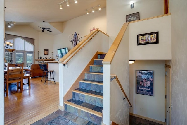 631 Parkview Dr, Steamboat Springs, CO 80487 - stairway featuring a ceiling fan, rail lighting, wood finished floors, and high vaulted ceiling